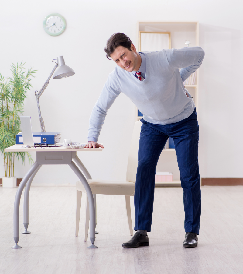 image of a person in a suit leaning on a desk. With the ergonomics and physiotherapy program can help to enhance workplace wellness in India.