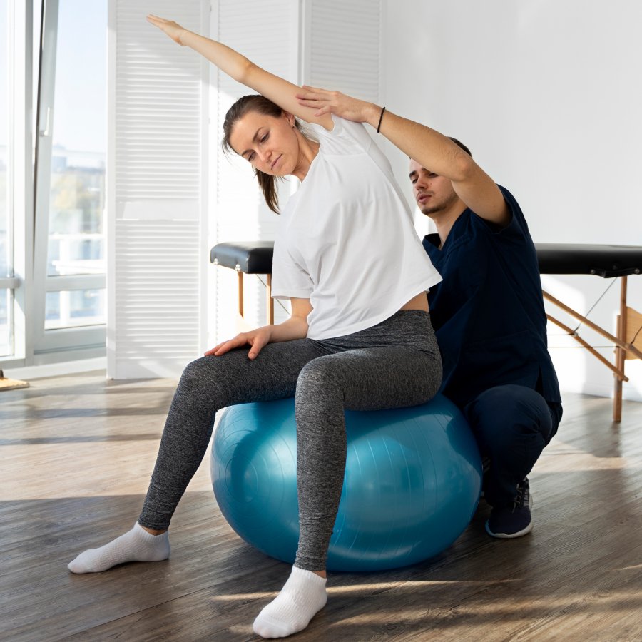 A woman and a man sitting on an exercise ball, engaging in a fitness activity together.